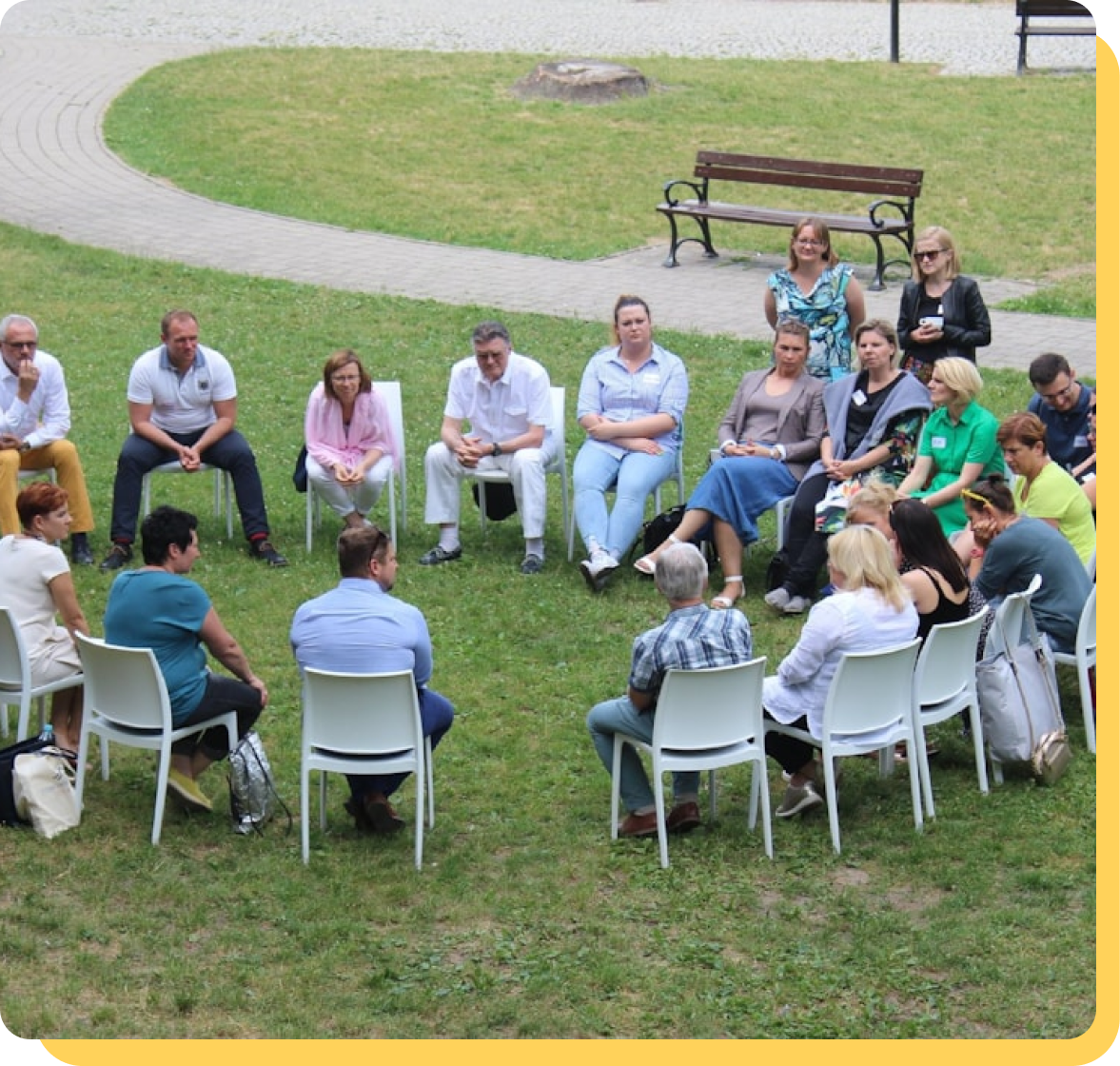 A large group seated in a circle during an outdoor therapist-led session